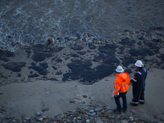 PHOTO: Officials walk along an the oil-covered coastline on 19,  2015 north of Goleta,  Calif.